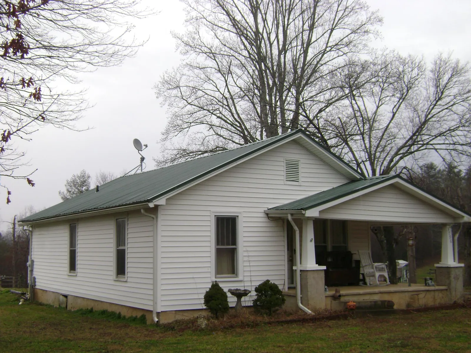 Green metal roof on a white bungalow with a side porch in Gardner
