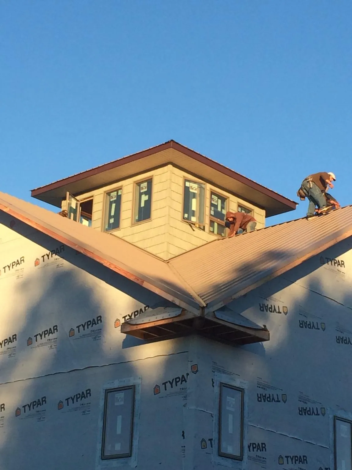 Roofers working around a rooftop cupola on a new metal roof at sunset — Roof Waterproofing in Gardner by Roofing Brothers